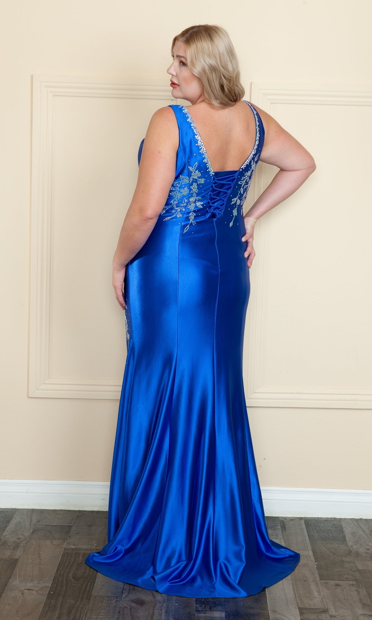 A woman faces away from the camera in the Plus-Size Long Spandex Prom Dress with Beads W1132, a floor-length gown in royal blue featuring silver bead embellishments on the back.